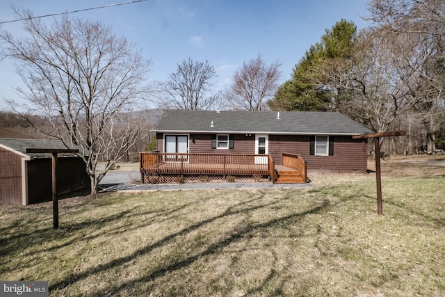 rear view of house featuring a yard, roof with shingles, and a deck