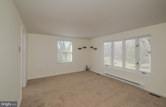 carpeted empty room with baseboard heating, plenty of natural light, baseboards, and visible vents