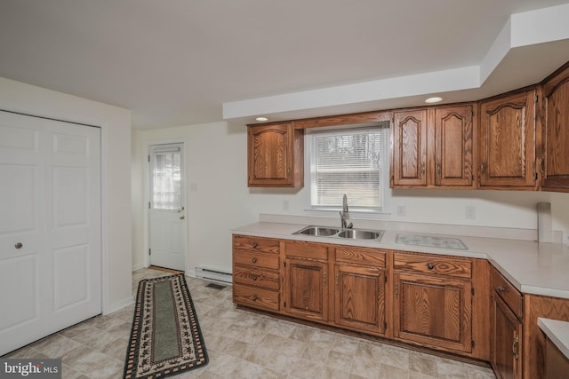 kitchen with brown cabinetry, baseboard heating, and a sink