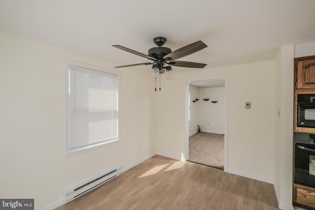 interior space with a baseboard heating unit, baseboards, light wood-style floors, and a ceiling fan