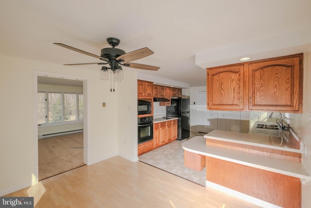 kitchen with a baseboard radiator, a sink, ceiling fan, black appliances, and brown cabinets