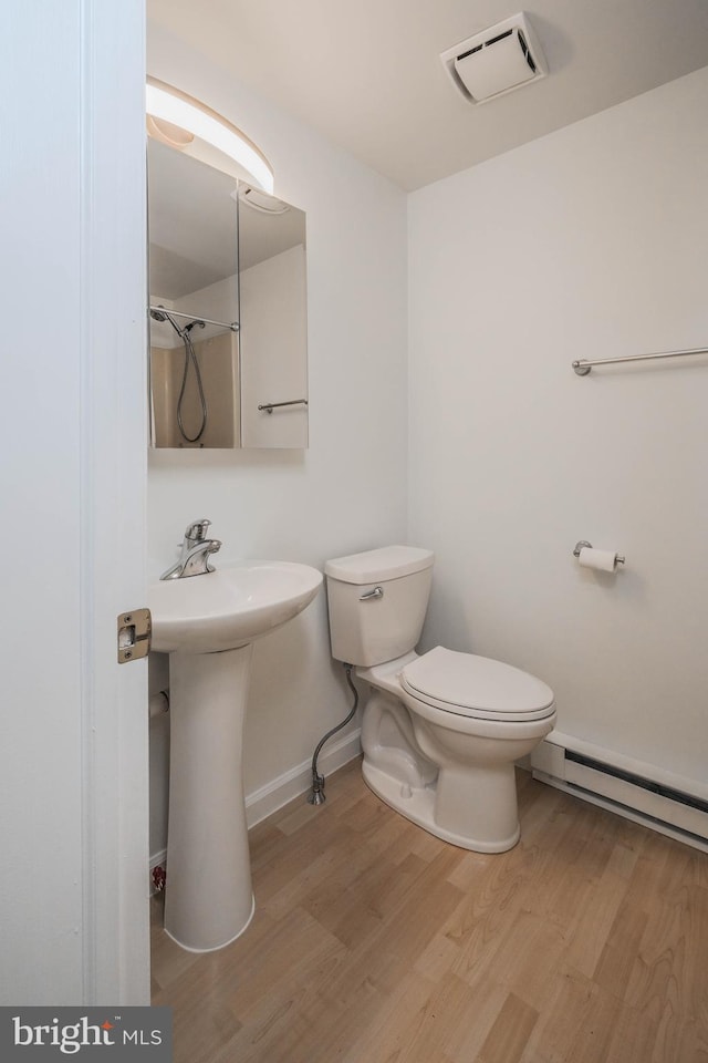 bathroom with wood finished floors, visible vents, baseboards, toilet, and baseboard heating