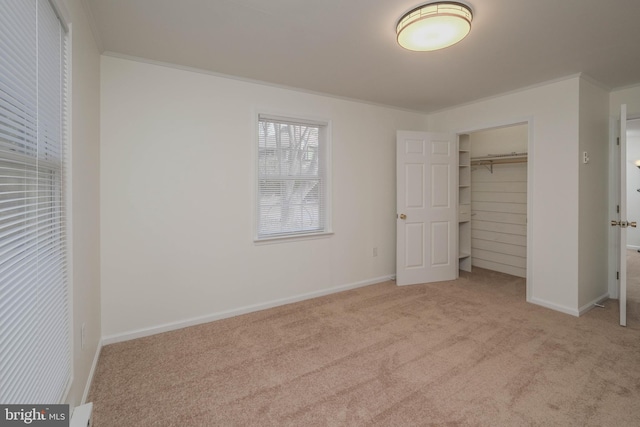 unfurnished bedroom featuring crown molding, a closet, baseboards, and carpet floors