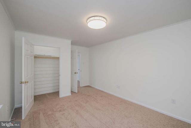 unfurnished bedroom with a closet, carpet floors, baseboards, and ornamental molding