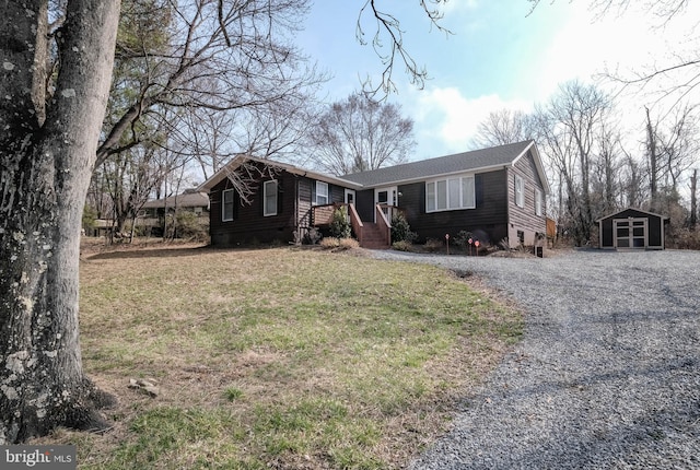 view of front of property with gravel driveway, an outdoor structure, and a front yard