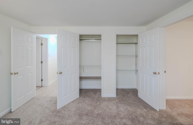 unfurnished bedroom with carpet flooring, baseboards, and multiple closets