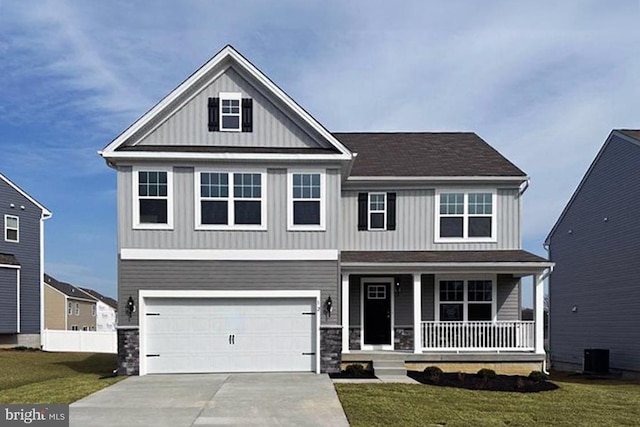 craftsman house with driveway, a porch, an attached garage, a front lawn, and board and batten siding