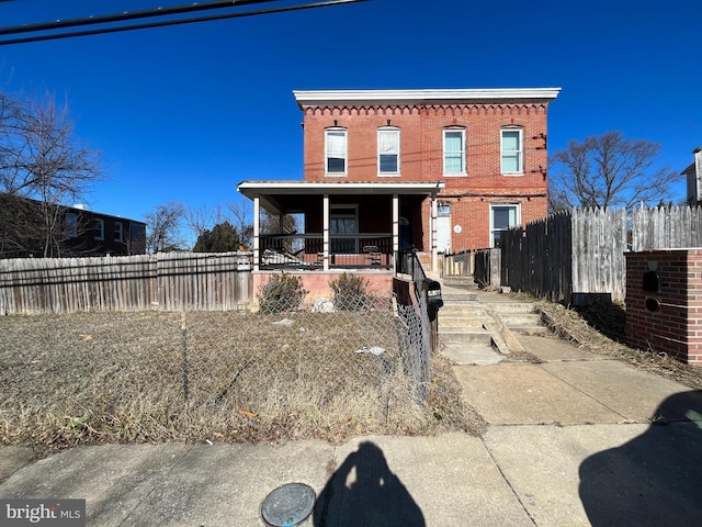 view of front of house featuring a fenced front yard, brick siding, and covered porch