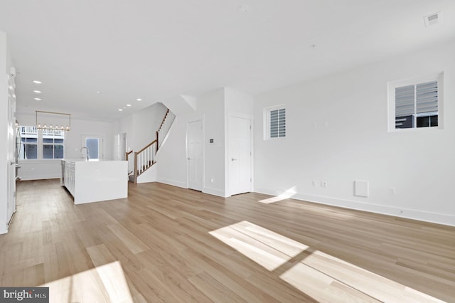 unfurnished living room featuring visible vents, baseboards, stairs, recessed lighting, and light wood-style floors