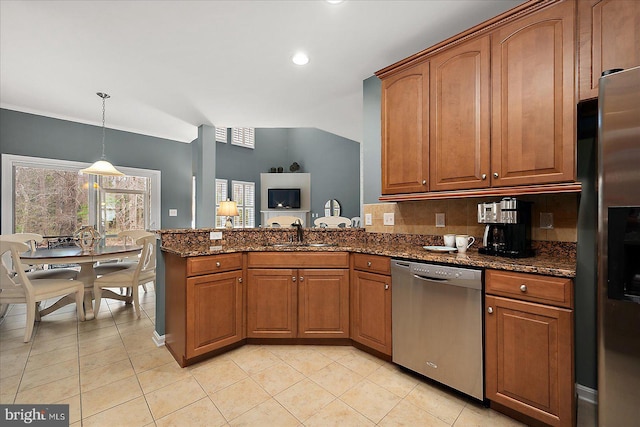 kitchen with a sink, dark stone counters, appliances with stainless steel finishes, a peninsula, and brown cabinetry