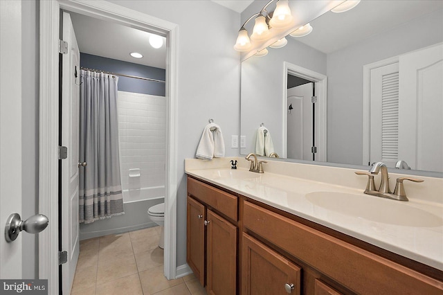 bathroom featuring tile patterned floors, toilet, double vanity, and a sink