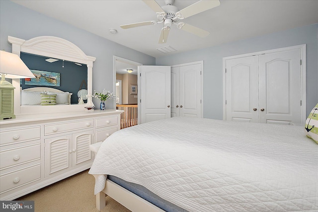 bedroom with a ceiling fan, visible vents, and two closets