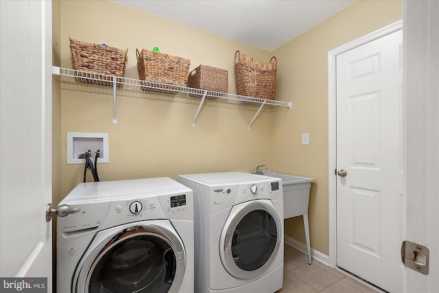 washroom featuring a sink, separate washer and dryer, light tile patterned flooring, and laundry area