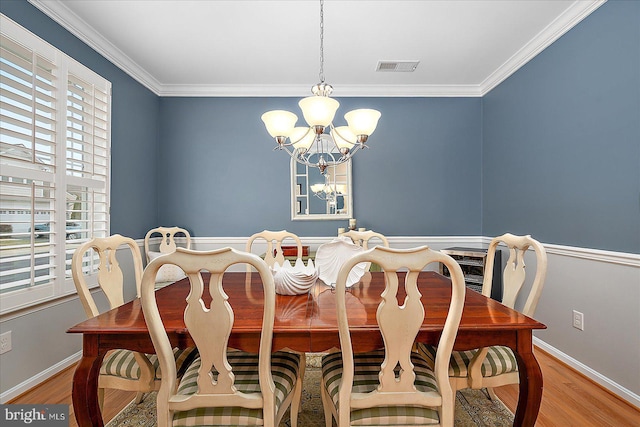 dining room with a notable chandelier, wood finished floors, visible vents, and baseboards