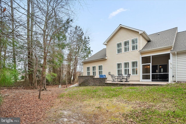 rear view of property with a patio area, a yard, roof with shingles, and a sunroom