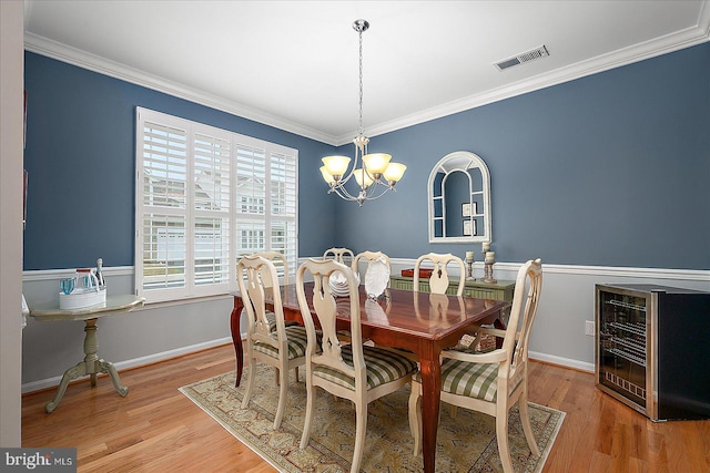 dining room with visible vents, light wood-style flooring, crown molding, and an inviting chandelier