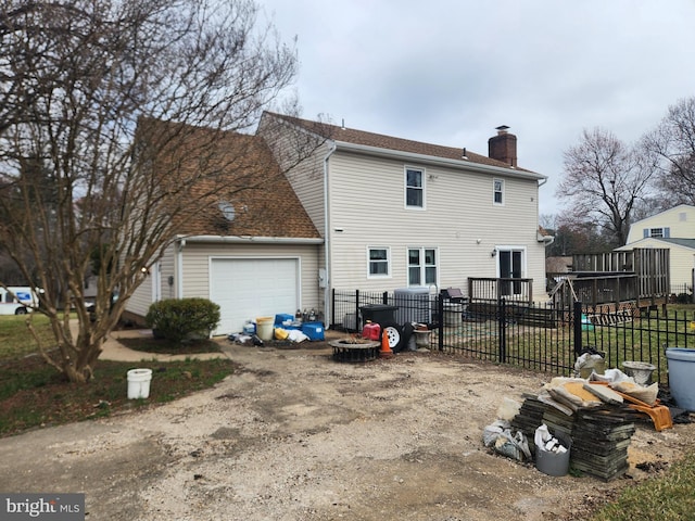 rear view of house with fence, a garage, driveway, and a chimney