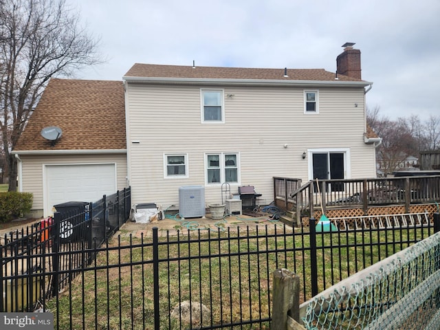 rear view of property featuring a wooden deck, a chimney, a fenced backyard, a yard, and an attached garage