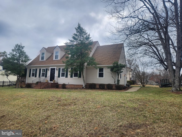 cape cod house with a shingled roof, a front yard, and fence