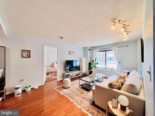 living area with a textured ceiling, baseboards, and wood finished floors