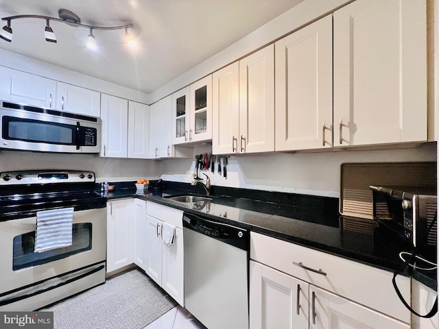 kitchen featuring white cabinetry, stainless steel appliances, glass insert cabinets, and a sink