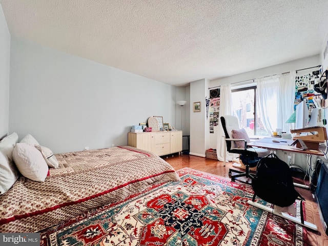 bedroom with a textured ceiling and wood finished floors