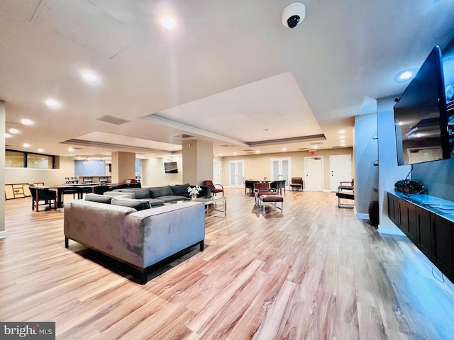 living room featuring visible vents, a tray ceiling, recessed lighting, light wood-style floors, and baseboards