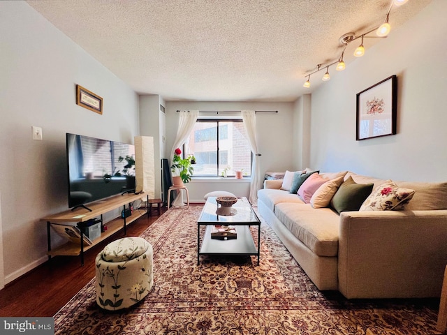 living room featuring baseboards, a textured ceiling, wood finished floors, and rail lighting