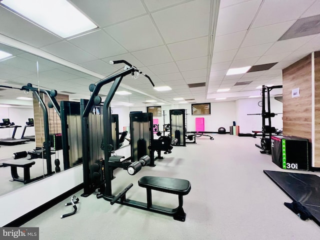 workout area featuring a paneled ceiling and wood walls