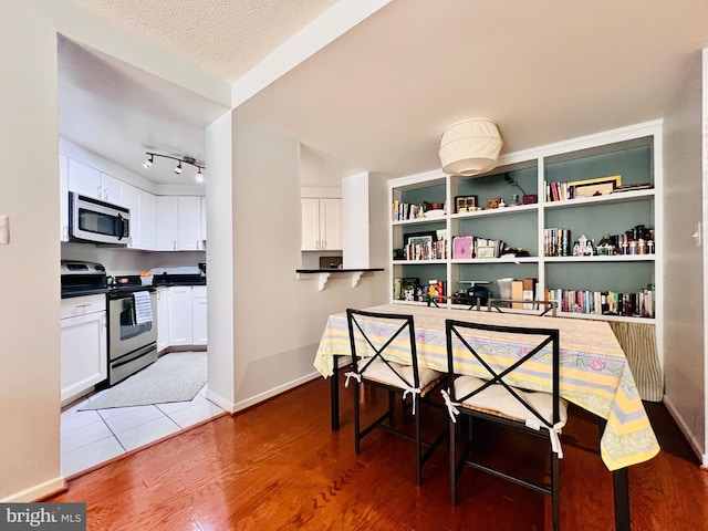 dining room with a textured ceiling, baseboards, and wood finished floors