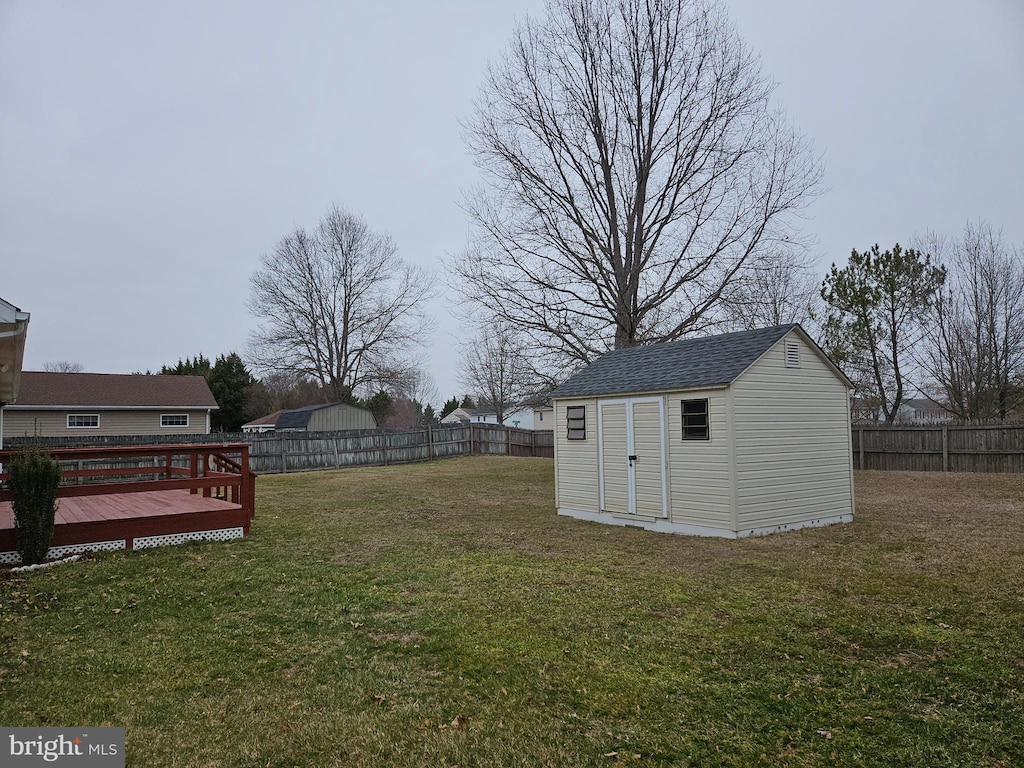 view of yard with an outbuilding, a storage unit, a fenced backyard, and a wooden deck