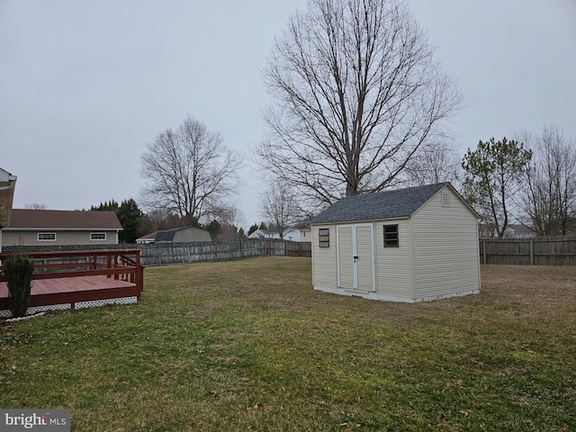 view of yard with an outbuilding, a storage unit, a fenced backyard, and a wooden deck