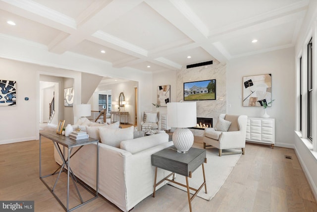 living area with baseboards, light wood finished floors, coffered ceiling, a fireplace, and beamed ceiling