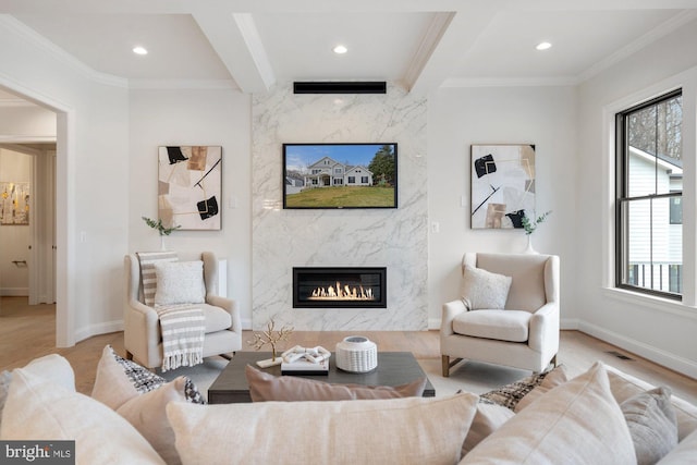 living area with beamed ceiling, wood finished floors, a fireplace, and crown molding