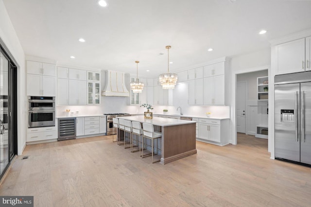 kitchen with premium range hood, wine cooler, a kitchen breakfast bar, an inviting chandelier, and high end appliances