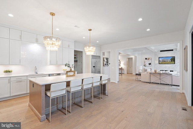 kitchen featuring a sink, stainless steel built in fridge, light wood finished floors, and a chandelier