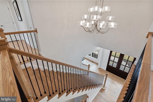 staircase featuring an inviting chandelier, wood finished floors, and baseboards