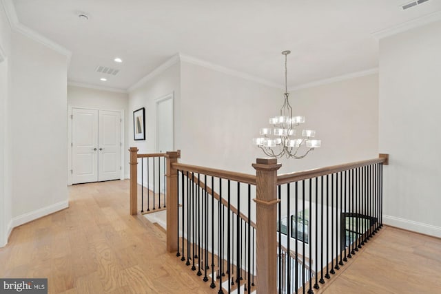 hall with light wood-style floors, an upstairs landing, visible vents, and baseboards