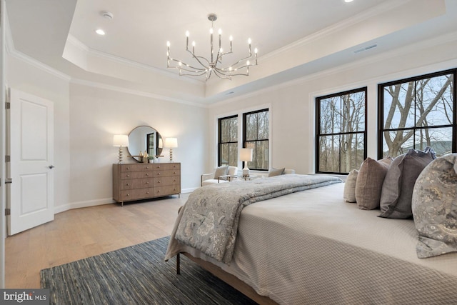 bedroom with light wood-type flooring, ornamental molding, a tray ceiling, baseboards, and a chandelier