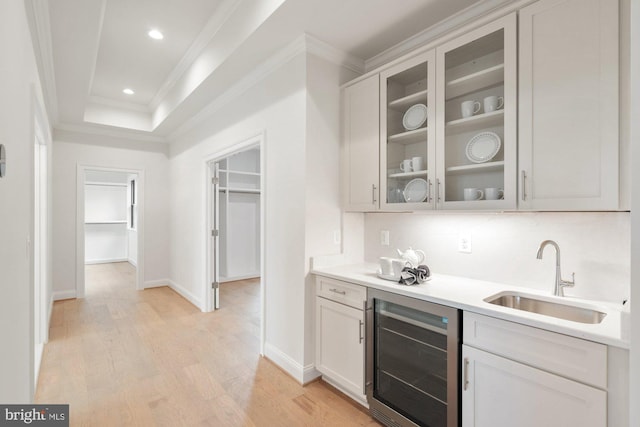 kitchen featuring crown molding, beverage cooler, light wood-style floors, and a sink