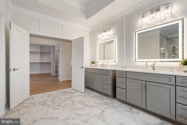 bathroom featuring two vanities, a stall shower, ornamental molding, a sink, and marble finish floor