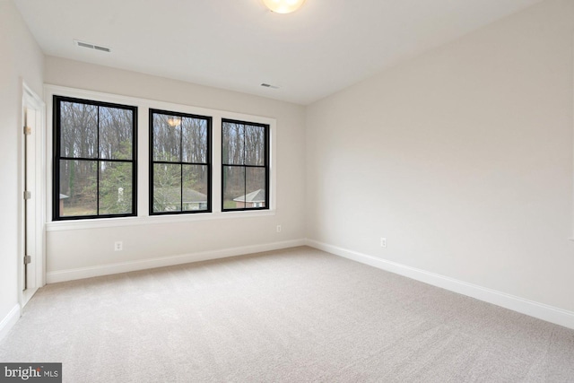 unfurnished room featuring visible vents, light carpet, and baseboards