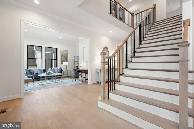 staircase featuring recessed lighting, ornamental molding, baseboards, and wood finished floors