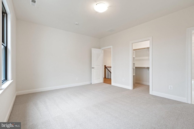 unfurnished bedroom featuring visible vents, a closet, carpet flooring, baseboards, and a spacious closet