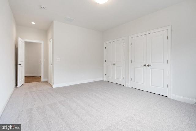 unfurnished bedroom with recessed lighting, carpet, multiple closets, and baseboards