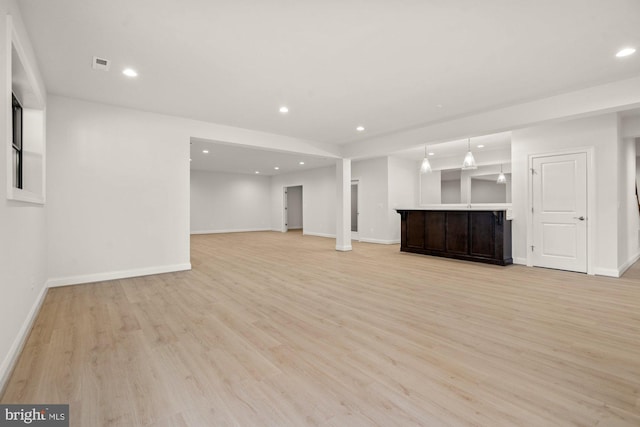 unfurnished living room with recessed lighting, light wood-style flooring, bar area, and baseboards