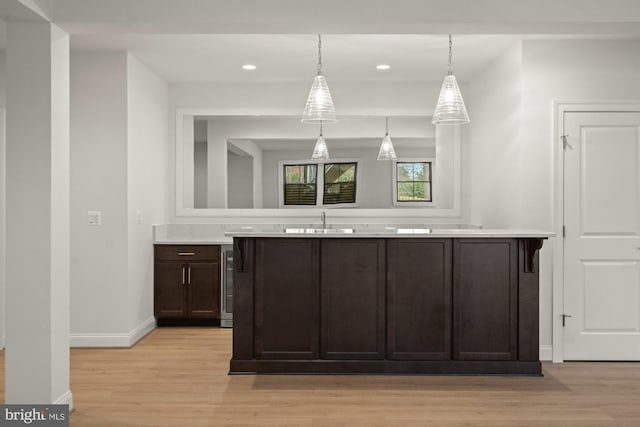 kitchen with baseboards, dark brown cabinetry, light wood-style flooring, and light countertops