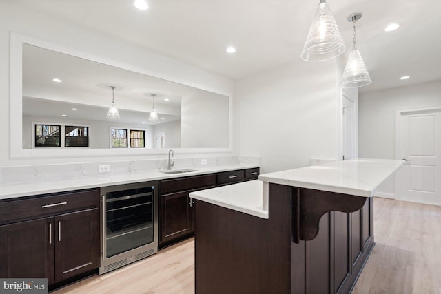 kitchen with wine cooler, recessed lighting, light wood-style floors, and a sink