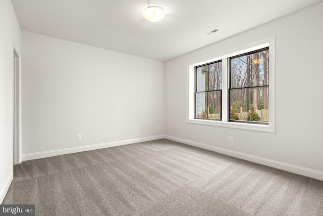 carpeted spare room featuring baseboards and visible vents