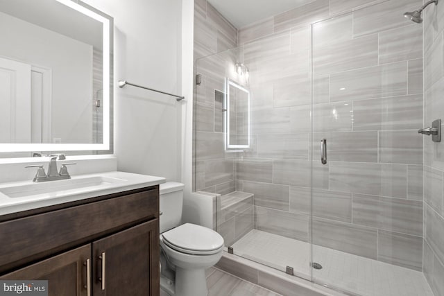 bathroom featuring vanity, toilet, and a shower stall